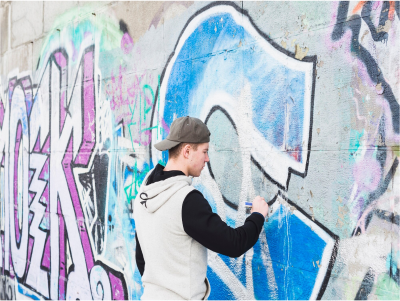 Young man spray painting graffiti on a wall